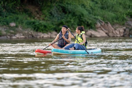 Téléchargez les photos : En vacances d'été couple amoureux se détendre voile planche à voile surf sur la rivière sur la belle nature calme rivière - en image libre de droit
