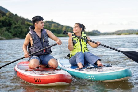 Téléchargez les photos : En vacances d'été couple amoureux se détendre voile planche à voile surf sur la rivière sur la belle nature calme rivière - en image libre de droit
