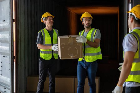 Téléchargez les photos : Le travailleur porte une boîte en carton tirée d'un conteneur en acier de 40 pieds sur le parc de camions-remorques à l'entrepôt - en image libre de droit
