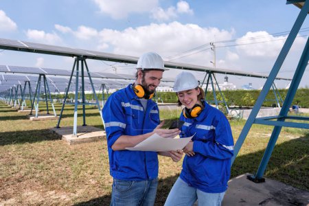 Téléchargez les photos : Ingénieurs à la ferme solaire à l'heure de pause regardant les médias sociaux drôles de téléphone mobile et rire - en image libre de droit