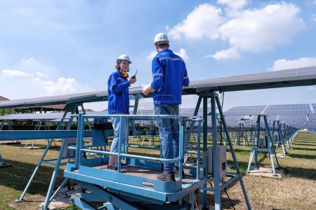 Téléchargez les photos : Ingénieurs d'entretien au stand de ferme solaire sur ascenseur à ciseaux, inspection de routine de l'état des panneaux solaires - en image libre de droit