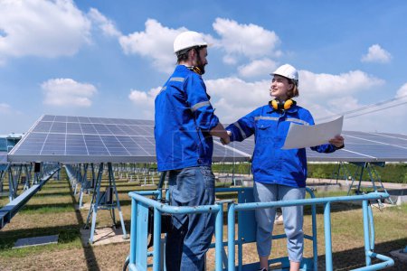 Foto de Ingenieros de mantenimiento en el puesto de granja solar en los paneles solares de inspección de elevación de tijera y estrechando las manos - Imagen libre de derechos
