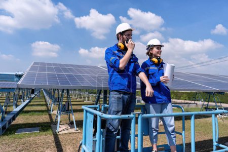 Foto de Ingenieros de mantenimiento en el puesto de granja solar en elevador de tijeras, inspección de paneles solares e informes de radio - Imagen libre de derechos