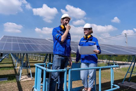 Foto de Ingenieros de mantenimiento en el puesto de granja solar en elevador de tijeras, inspección de paneles solares e informes de radio - Imagen libre de derechos