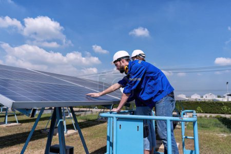 Téléchargez les photos : Ingénieurs d'entretien au stand de ferme solaire sur ascenseur à ciseaux, inspection de routine de l'état des panneaux solaires - en image libre de droit