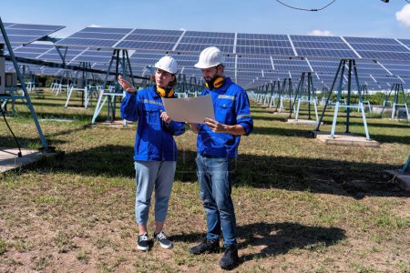 Foto de Ingenieros de mantenimiento en la granja solar mirando dibujo discutir sobre la ampliación actualizar la planta de electricidad - Imagen libre de derechos