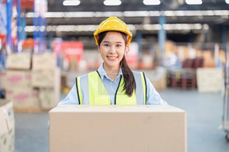 Photo for Staff working in large depot storage warehouse lift up heavy carton box smiling portrait - Royalty Free Image
