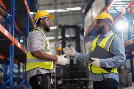 Photo for African americans working in warehouse, checking forklift truck, loading carton boxes, smiling and check hands - Royalty Free Image