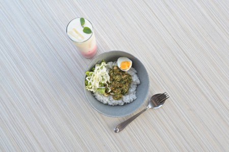 Téléchargez les photos : Green chili squid rice with salad and pink lava drink on wooden table or in indonesia called nasi cumi cabe ijo (natural light) - en image libre de droit