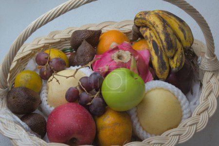 Téléchargez les photos : A basket of natural fresh fruits on a white table. - en image libre de droit