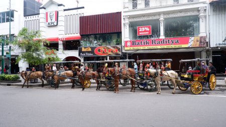 Téléchargez les photos : Yogyakarta- Indonesia December 27,2022 : Delman or Andong is Indonesian traditional transportation, a horse-drawn carriage on the side of the Malioboro Jogja road. - en image libre de droit