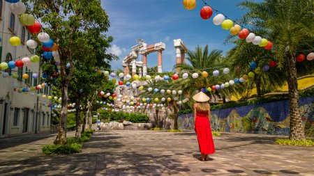 Téléchargez les photos : Jeune femme en robe rouge et chapeau vietnamien explorant Sunset Town sur l'île de Phu Quoc au Vietnam. - en image libre de droit