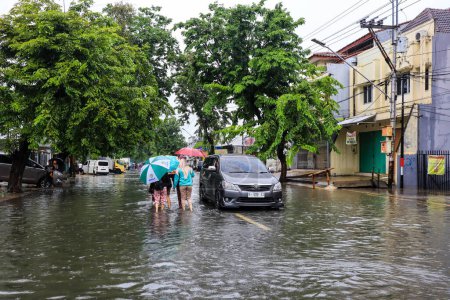 Téléchargez les photos : Semarang, December 2022. Some people are walking through the flood that hit the Poncol train station area and some residents are preparing to evacuate. vehicles hit the flood. - en image libre de droit