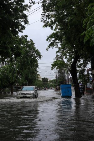 Téléchargez les photos : Semarang, December 2022. Some people are walking through the flood that hit the Poncol train station area and some residents are preparing to evacuate. vehicles hit the flood. - en image libre de droit