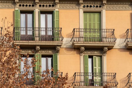 Téléchargez les photos : Traditional Barcelona style balconies and green wooden shuttered windows on facade of the renovated house on a sunny day, in the old city of the center. - en image libre de droit
