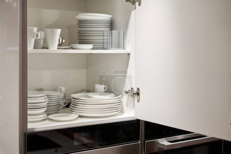 Photo for Glasses, dishes and bowls in a cabinet in a kitchen. Kitchen storage organization. Details of the interior of the kitchen in the house. High quality photo - Royalty Free Image