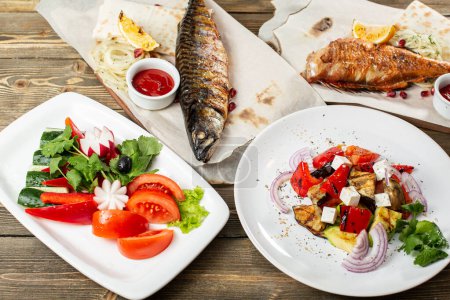 Photo for Grilled mackerel and a salad of fresh vegetables. Serving on a wooden Board on a rustic table. Barbecue restaurant menu, a series of photos of different meats anf fish. - Royalty Free Image