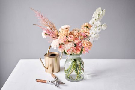 Téléchargez les photos : Arrangement de fleurs finies dans un vase pour la maison. Bouquet de fleurs, prêt pour l'intérieur. Fleurs fraîches coupées pour la maison de décoration. Fleuriste européen. Livraison fleur fraîche coupée - en image libre de droit