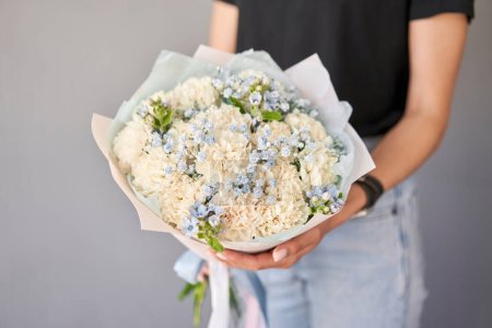 Small Beautiful bouquets of mixed flowers in woman hand. Floral shop concept . Beautiful fresh cut bouquet. Flowers delivery. High quality photo