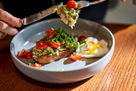 Photo for Open brioche sandwich with mint avocado, poached egg served with arugula and cherry tomato. Healthy breakfast. Toast with guacamole, vegetable and poached egg and eggs benedict with brioche. - Royalty Free Image