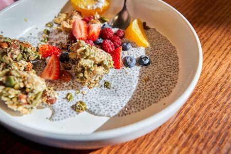 Photo for Chia pudding with homemade coconut granola, peanut butter and berries in gray bowl. Healthy plant based diet, detox, summer recipe. Breakfast in the Restaurant. High quality photo - Royalty Free Image