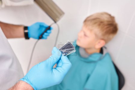 Röntgenuntersuchung der Zähne eines Jungen mit einem digitalen Röntgengerät in einer Kinderzahnklinik. Zahnarzt bereitet Jungen auf Zahnröntgenbild in Zahnklinik vor