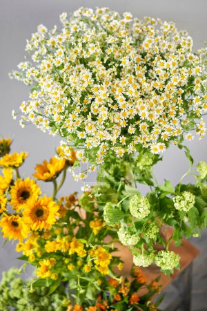 Photo for A colorful display of yellow and white flowers, consisting of herbaceous plants and annual flowers, adorns the tabletop - Royalty Free Image