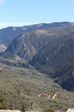 Delphi schmiegt sich inmitten der atemberaubenden Umarmung hoch aufragender Berge, deren schroffe Gipfel und grüne Hänge eine atemberaubende Kulisse für den zeitlosen Reiz und die historische Bedeutung der antiken Stätte bieten