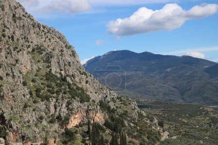 Delphi schmiegt sich inmitten der atemberaubenden Umarmung hoch aufragender Berge, deren schroffe Gipfel und grüne Hänge eine atemberaubende Kulisse für den zeitlosen Reiz und die historische Bedeutung der antiken Stätte bieten