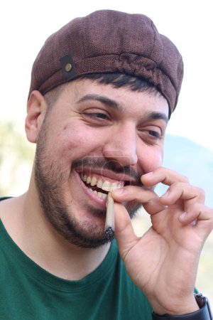 In einer Szene des unbeschwerten Genusses lacht ein Mann mit einem beträchtlichen Joint, der aus seinem Mund baumelt, herzlich und verkörpert den entspannten Lebensstil und die neu gewonnenen Freiheiten, die die Cannabis-Legalisierung mit sich bringt.