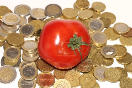 Une tomate perchée au sommet d'une pile de pièces symbolise l'intersection de l'inflation, de l'agriculture et du prix des produits
