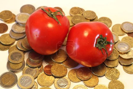 A tomato perched atop a stack of coins symbolizes the intersection of inflation, agriculture, and the price of produce
