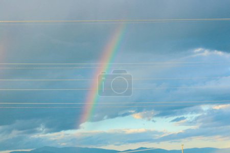 Begeben Sie sich auf eine visuelle Reise, während Sie die atemberaubende Schönheit eines Regenbogens vor dem Hintergrund dramatischer Wolken einfangen