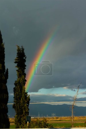 Begeben Sie sich auf eine visuelle Reise, während Sie die atemberaubende Schönheit eines Regenbogens vor dem Hintergrund dramatischer Wolken einfangen