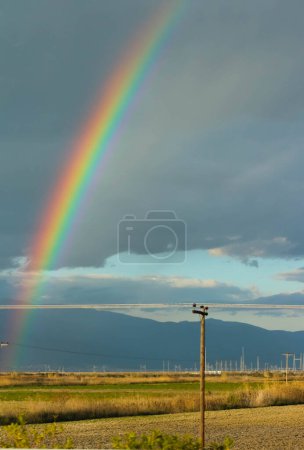 Embark on a visual journey as you capture the stunning beauty of a rainbow set against a backdrop of dramatic clouds