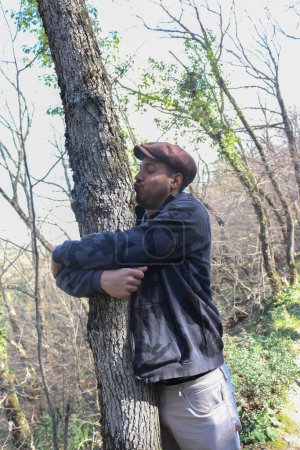 Photo for Witness the poignant moment as a young man envelops a majestic tree in a warm embrace - Royalty Free Image