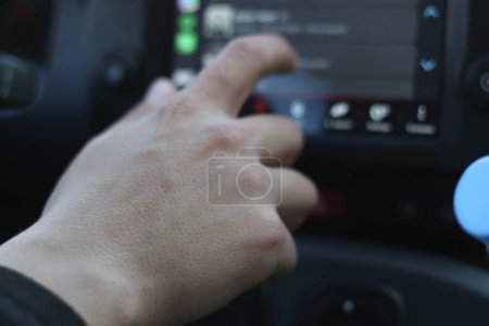 Witness the seamless fusion of technology and rhythm as a hand effortlessly navigates the car interface to change music, adding a melodic soundtrack to the journey