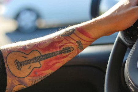 Embark on a journey where artistry meets motion as a tattooed arm commands the wheel with confidence and style