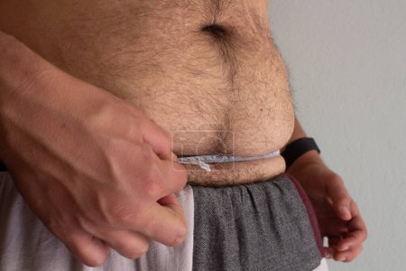 Erleben Sie die Reise eines übergewichtigen Mannes, der seine Gesundheit in die Hand nimmt und seine Taille mit Entschlossenheit inmitten sichtbarer Dehnungsstreifen misst