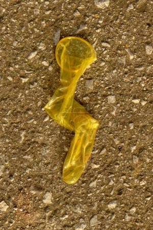 Entdecken Sie die raue Realität des urbanen Lebens mit diesem rohen und beunruhigenden Bild, in dem ein gebrauchtes Kondom auf dem Bürgersteig weggeworfen wird.