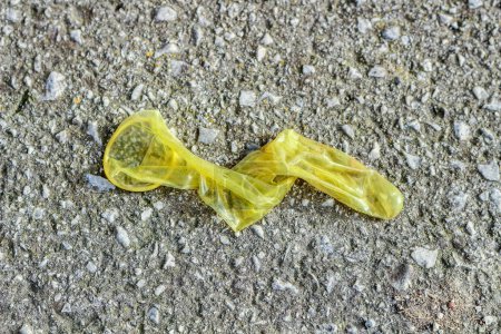 Uncover the harsh realities of urban life with this raw and unsettling image capturing a used condom discarded on the pavement.
