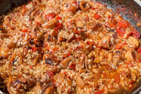 Erleben Sie den entscheidenden Moment, als Reis sich dem aromatischen Sofrito anschließt und die Essenz der traditionellen spanischen Paella unterstreicht