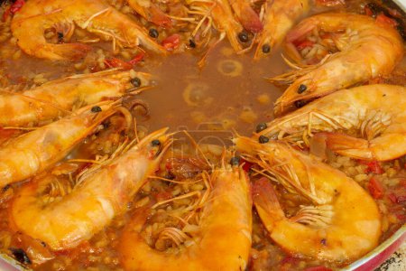 Vivez l'harmonie culinaire pendant que les crevettes dorées se joignent au vibrant mélange de saveurs de la paella espagnole traditionnelle, enrichissant chaque bouchée d'un délice salé.