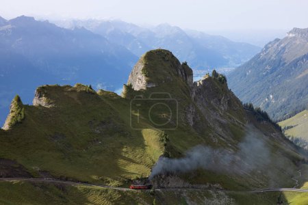 Téléchargez les photos : Superbe journée de randonnée dans les Alpes de Suisse. Une belle locomotive roule sur une montagne et beaucoup de fumée sort de la locomotive. Quelle vue en arrière-plan. - en image libre de droit