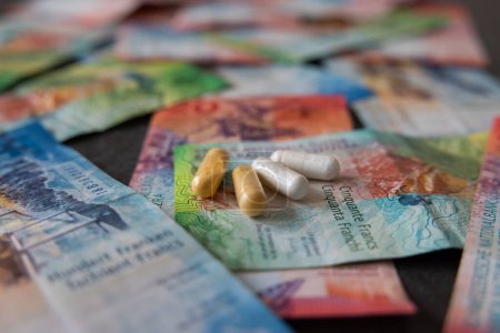 Foto de Los medicamentos se colocan simbólicamente en los billetes de banco del franco suizo. La inflación tampoco se detiene en la farmacia. - Imagen libre de derechos