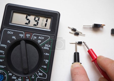 Composants électroniques semi-conducteurs. Test de diode avec multimètre numérique sur un blanc.
