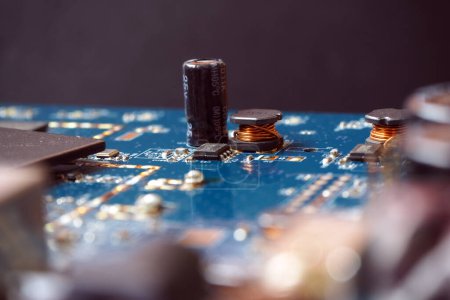 Photo for Close up of electronic component on a circuit board. Semiconductor chip, coil, capacitor on blue printed circuit card. - Royalty Free Image