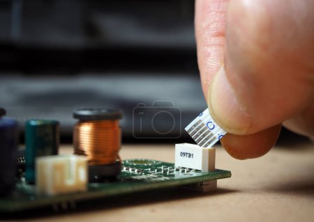 Photo for Technician plugging 6-pin flexible flat ribbon cable to the connector on electronic circuit board. - Royalty Free Image
