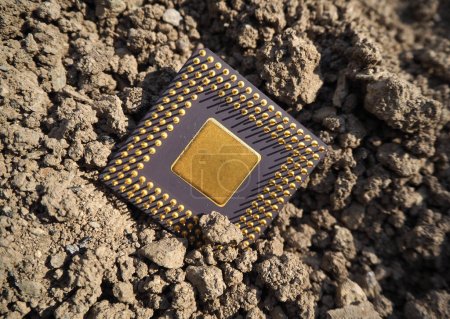 Un componente semiconductor enterrado en el suelo. Procesador en la arena.   