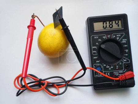 Photo for Lemon battery. Generating electric from a lemon and measuring its with voltmeter. Electrical voltage at millivolts levels. Bio battery. - Royalty Free Image